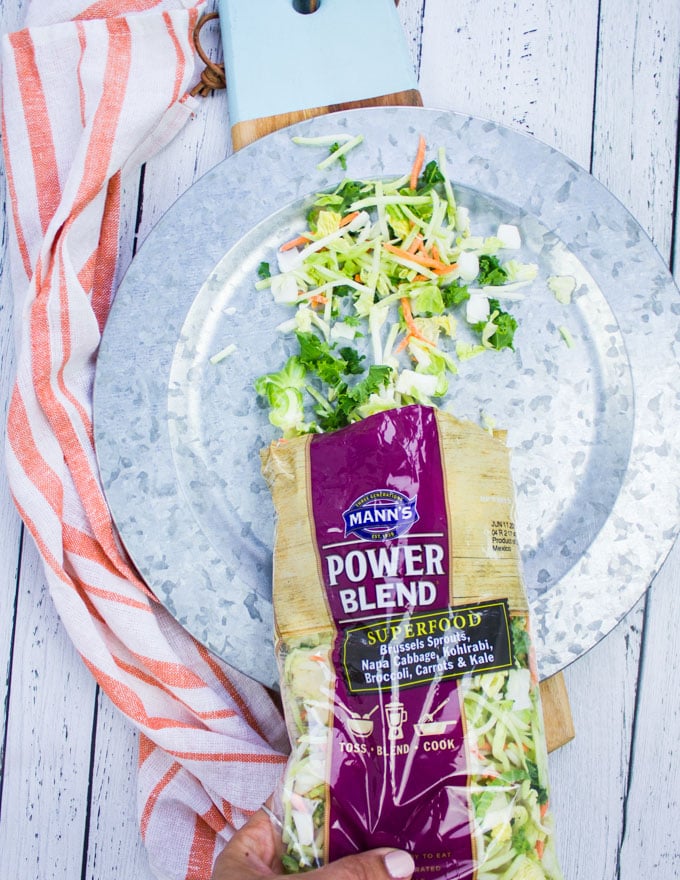 A hand pouring the slaw mix in to a plate