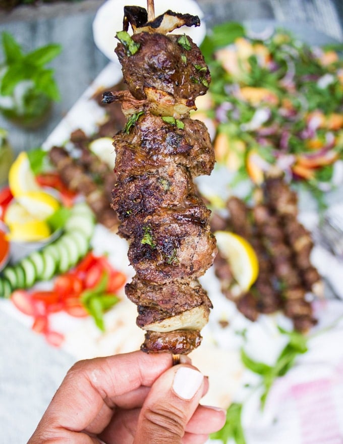One hand holding a Grilled Lamb Skewer closeup showing the final texture