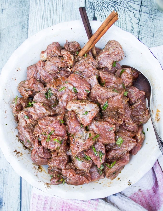The lamb chunks tossed with the marinade in a bowl with a spoon and ready for skewering