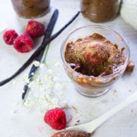 finished off scooped chocolate chia pudding in a cup and a spoon serving it with raspberries ontop for garnish