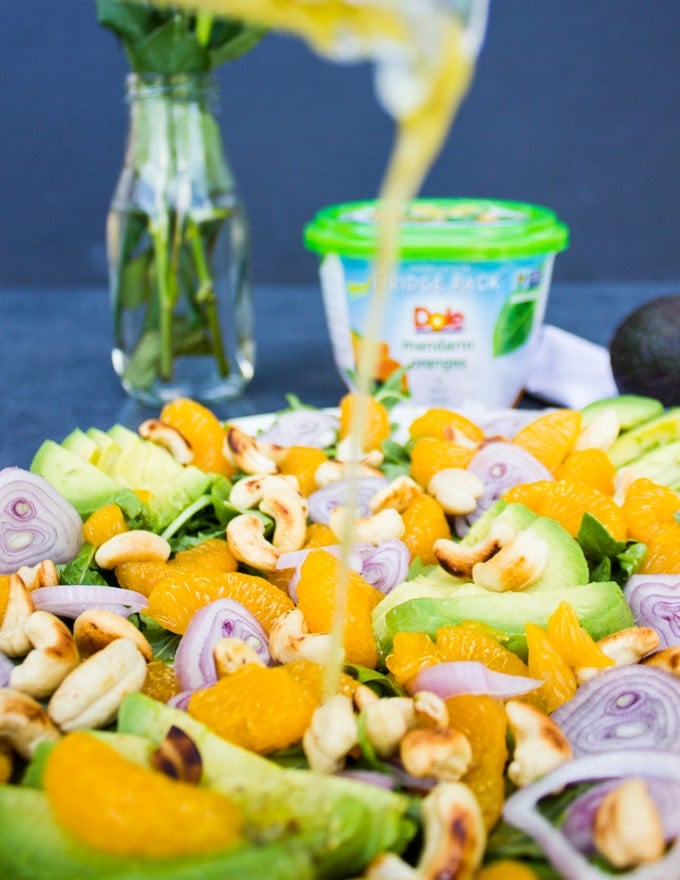 Citrus dressing being poured over the avocado salad