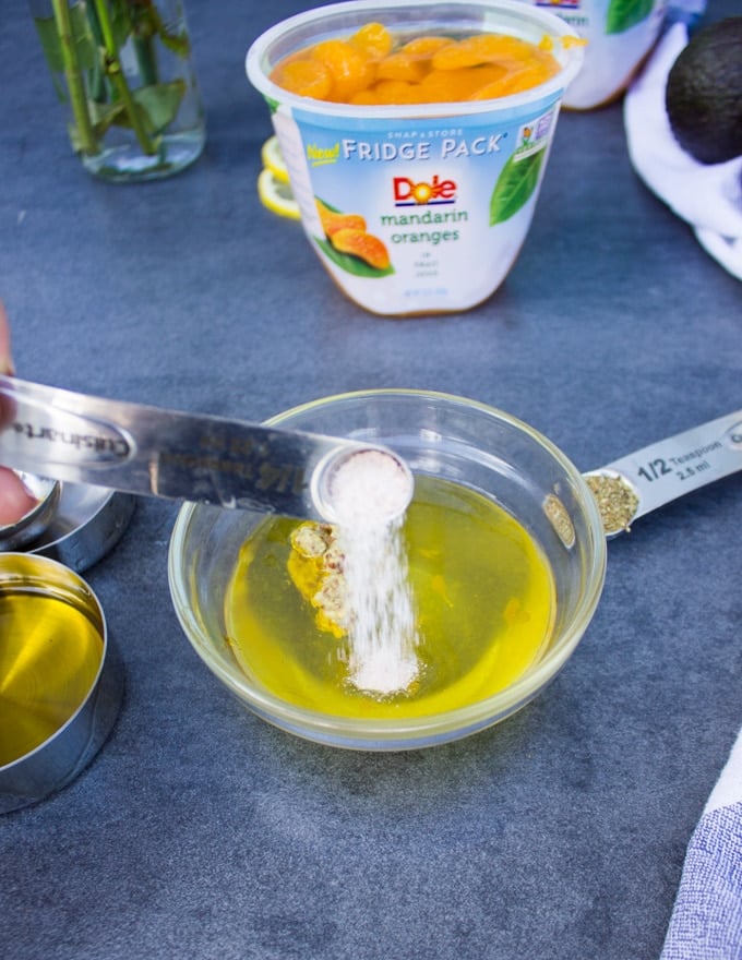 A spoon pouring some salt in to a bowl to make the citrus dressing