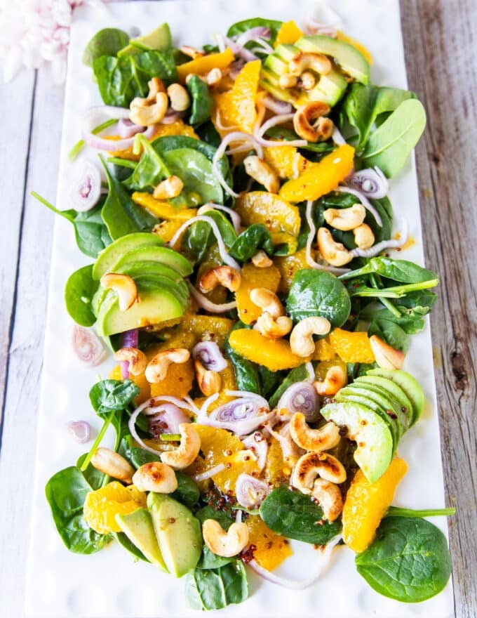 A plate of orange salad with avocado, nuts, orange segments