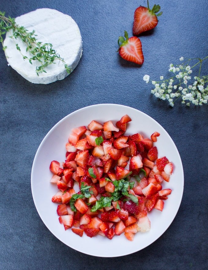 A bowl of finely diced strawberries with fresh basil and balsamic vinegar ready to fill the savory hand pies