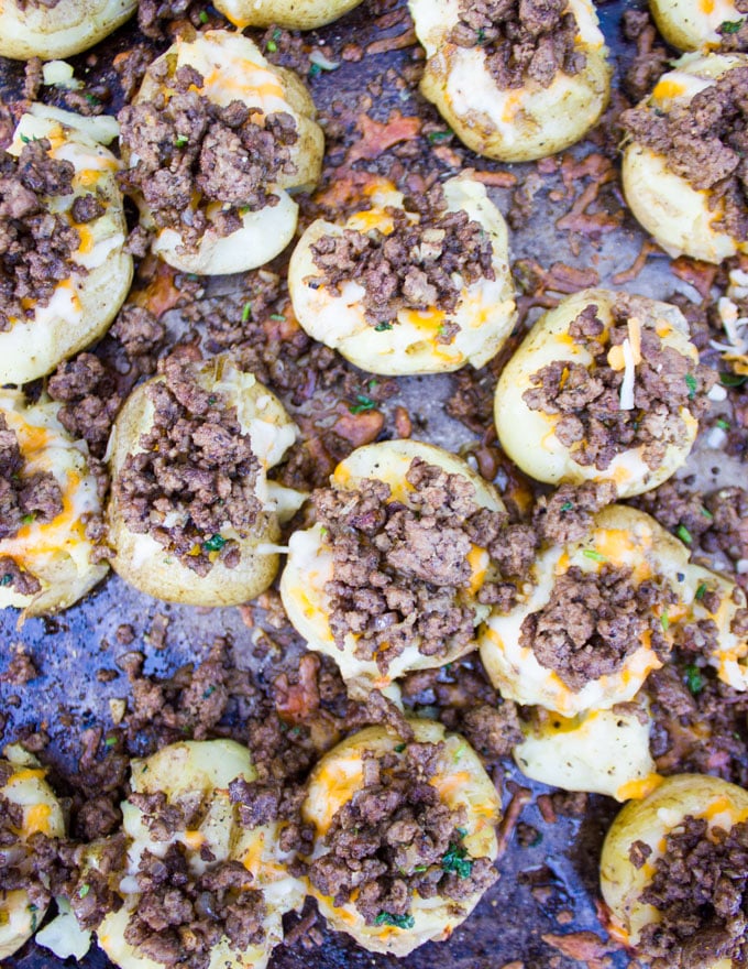 Adding lamb on the cheesy smashed potatoes