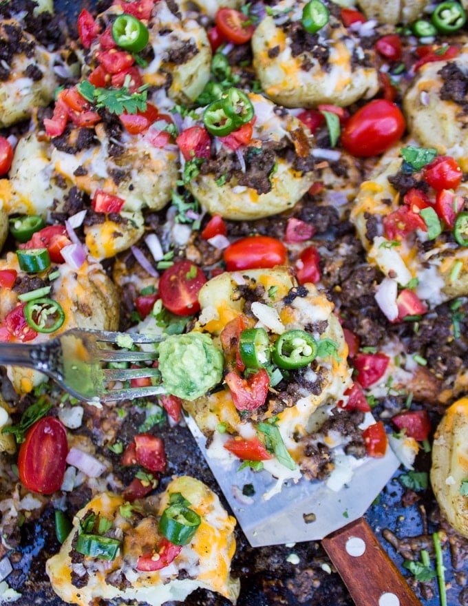 A close up of a smashed potato showing the ground lamb, green chilies, cheese, tomatoes, onions