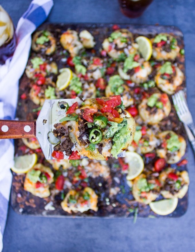 A spatula holding one smashed potato loaded with toppings and highlighting it