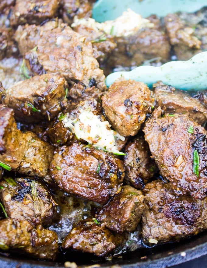 Finished steak bites in a pan drenched in cheese butter and ready to skewer. 