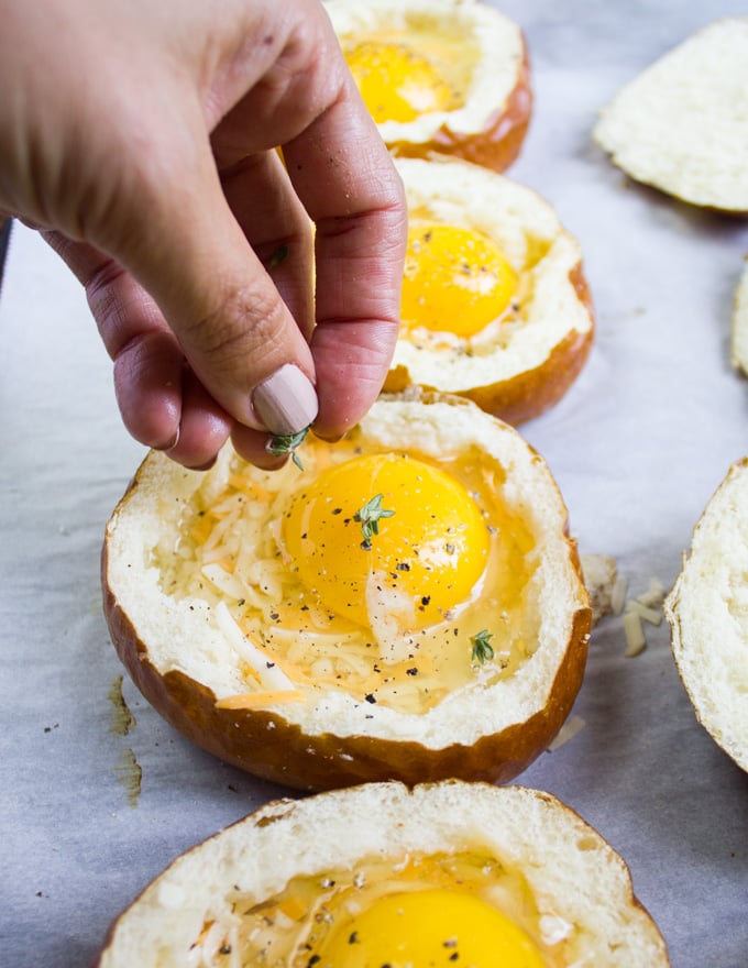 A hand sprinkling thyme over the eggs