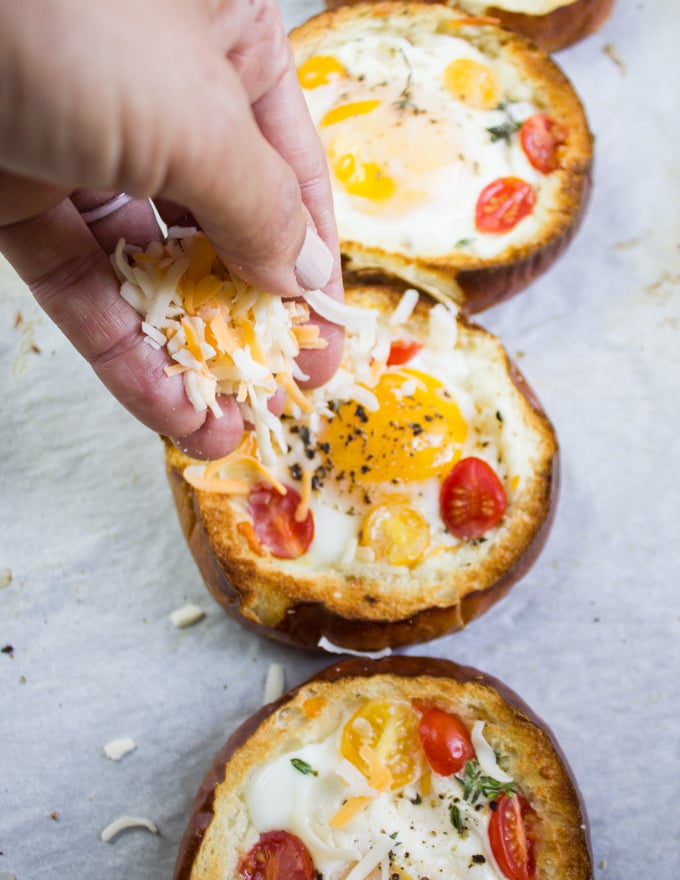 A hand sprinkling extra cheese over the baked eggs