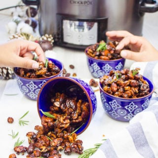 two hands grabbing the spiced mixed nuts from different bowls