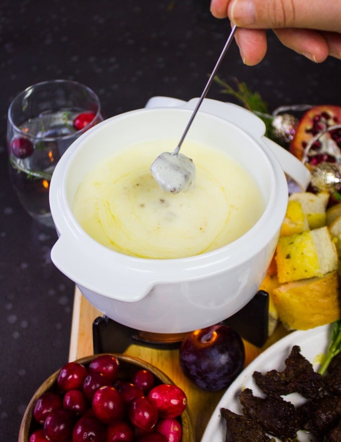 a fork dipping lamb dippers in the cheese fodnue pot