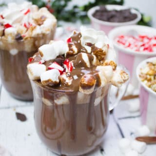 A close up of one cup of homemade hot chocolate with toppings and chocolate sauce