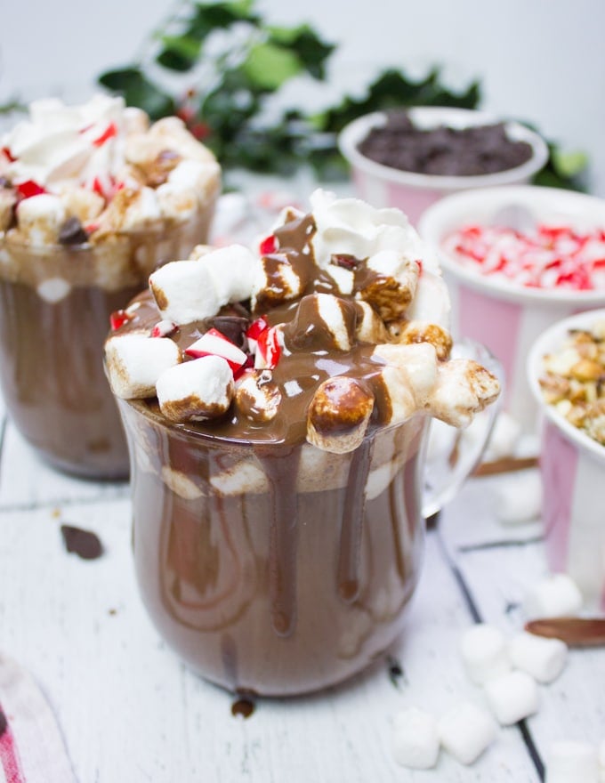 A close up of one cup of homemade hot chocolate with toppings and chocolate sauce