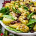 A close up of the potato salad with golden crust and spinach