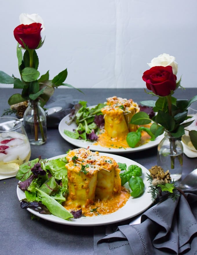 two plates ready to eat, two vases with roses, drinks and the perfect set up dinner for valentine's day