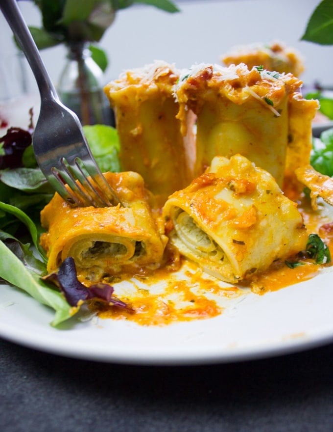 Finishing off the lasagna off the plate with a poon and fork showing the filling of the lasagna