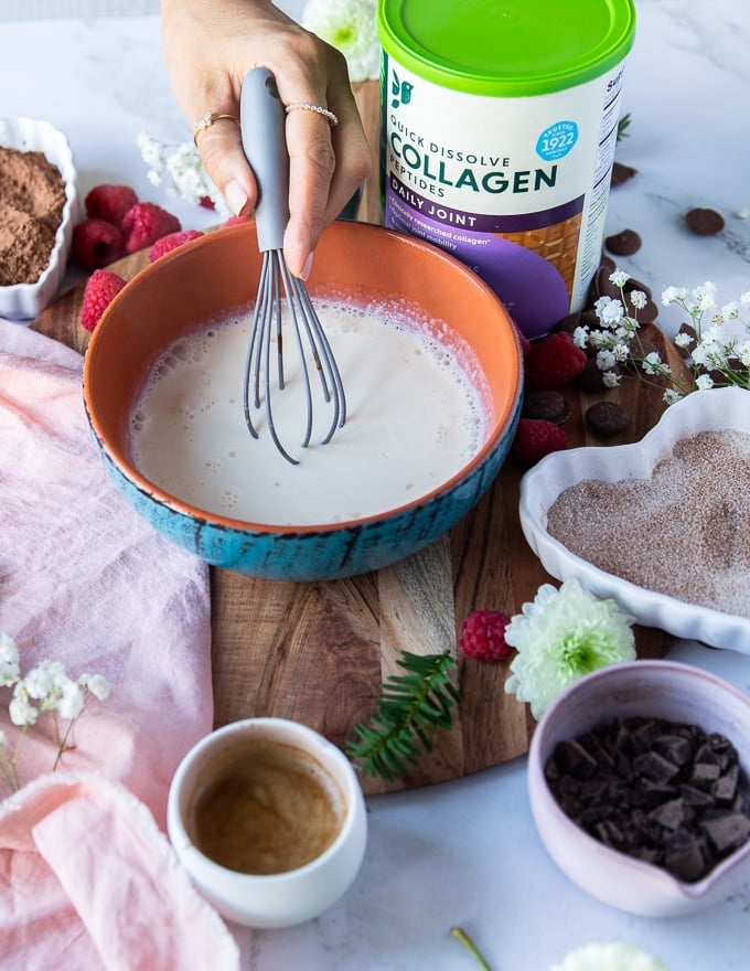 A hand whisking the cream and collagen together before adding the chocolate 