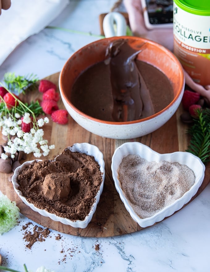 a coated chocolate truffle in cocoa powder in the bowl of cocoa powder