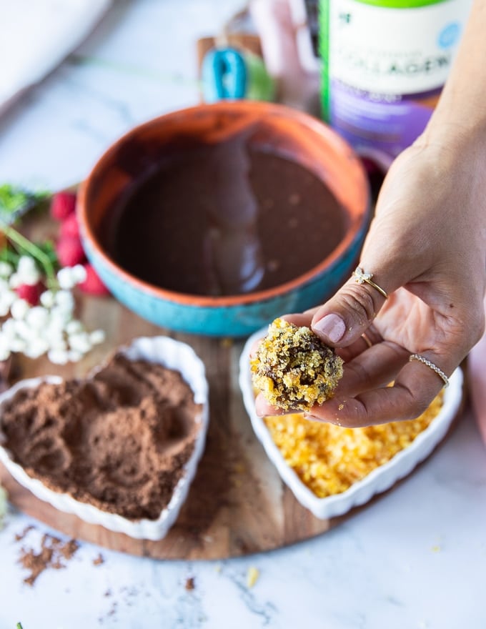 a hand holding a variation of chocolate truffles coated in caramel bits