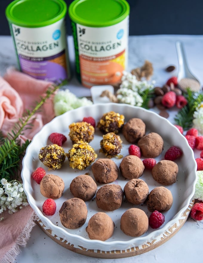 a plate of chocolate truffles on a white board surrounded by raspberries and chocolate chunks