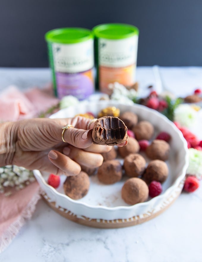 A hand holding a bitten off chocolate truffle to show how luscious and creamy it is on the inside