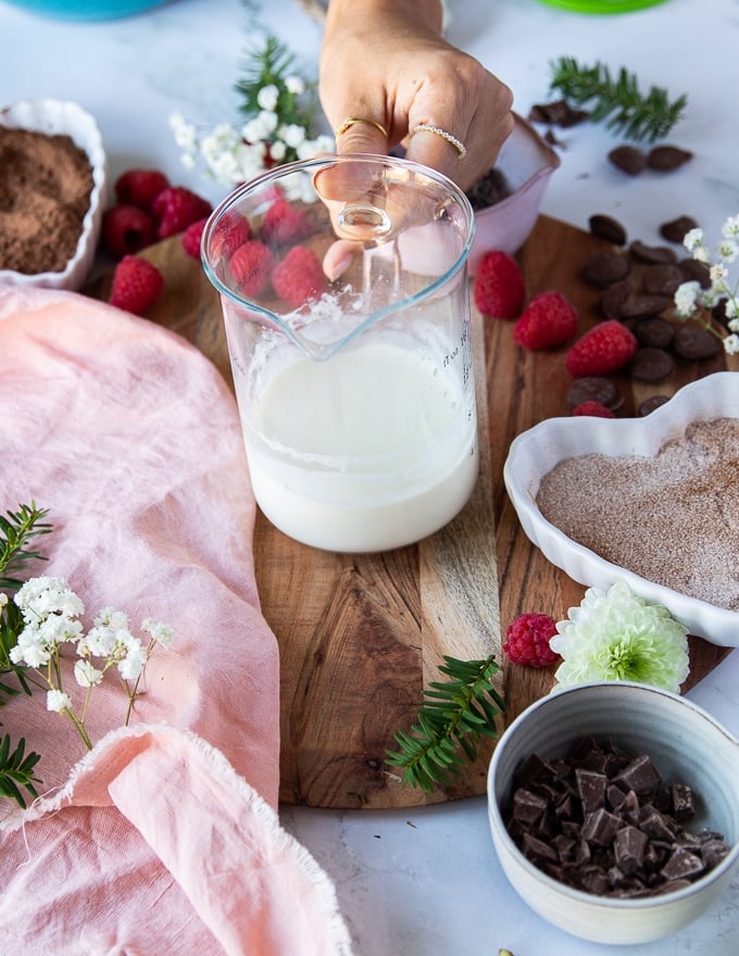 A hand holding a jar of hot heavy cream 