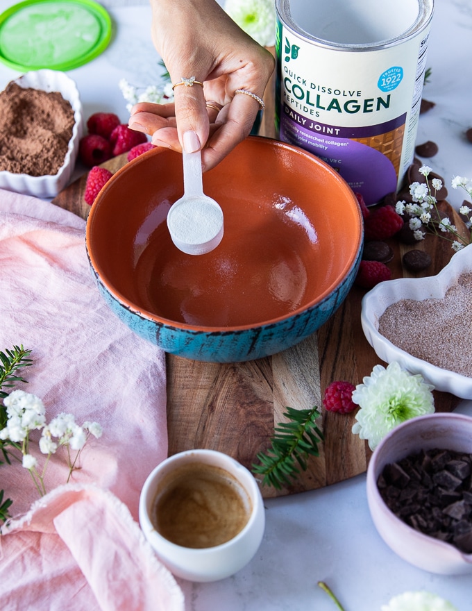 flavored collagen being added to the bottom of a bowl 