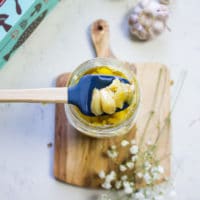 A spatula scoping some roasted garlic form the jar