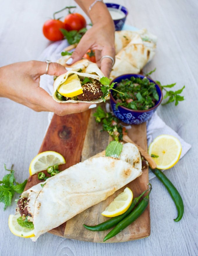 A hand Holding a falafel wrap showing the inside filing