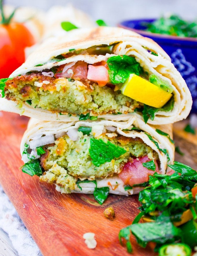 close uf of two falafel sandwiches cut in half and stacked over each other showing the filling and texture of falafel