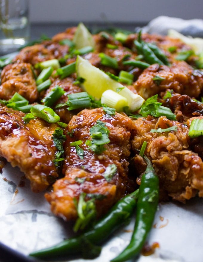 Close up of fried chicken strips with green chillies next to it and drizzled with the Korean Fried Chicken Sauce