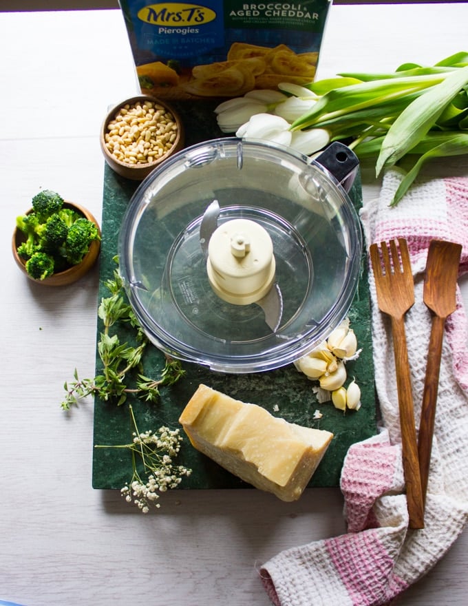 Ingredients for the broccoli pesto and a food processor to make it. Broccoli, parmesan cheese, garlic, pine nuts, herbs and olive oil