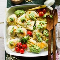 Pierogies out of the oven, sprinkled with broccoli pesto, parmesan cheese, pine nuts and chilli flakes