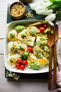 Pierogies out of the oven, sprinkled with broccoli pesto, parmesan cheese, pine nuts and chilli flakes
