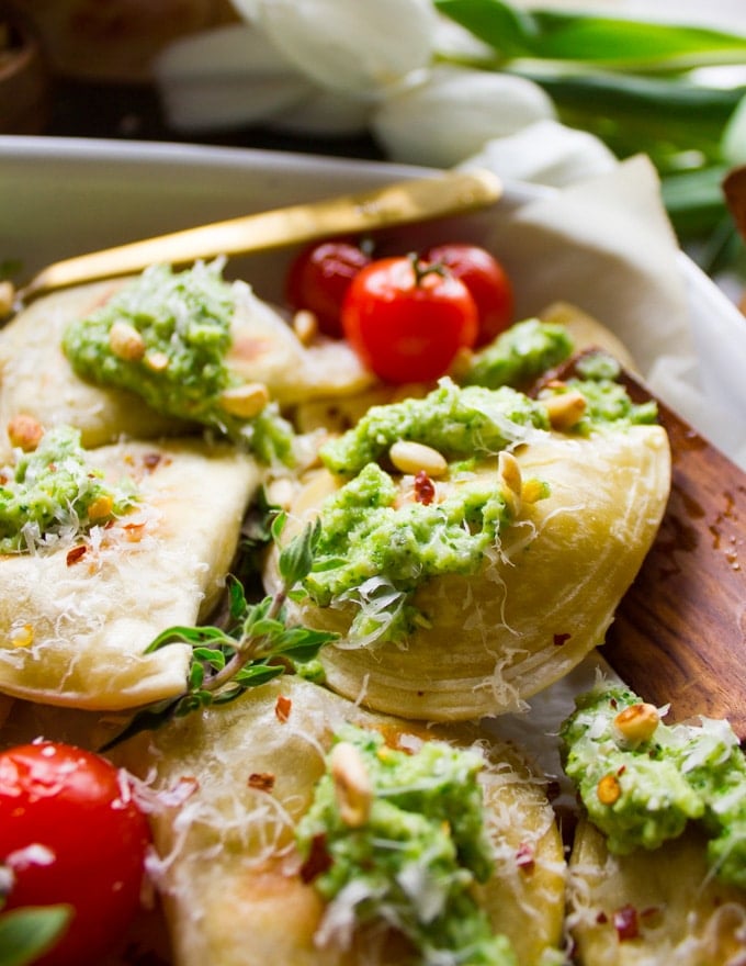 Close up of one baked pierogy with a dollop of broccoli pesto