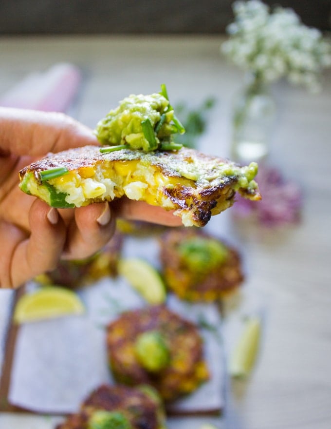 A hand holding a bitten corn fritter to show the inside