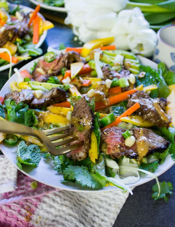 A fork eating a piece of lamb with the Thai salad