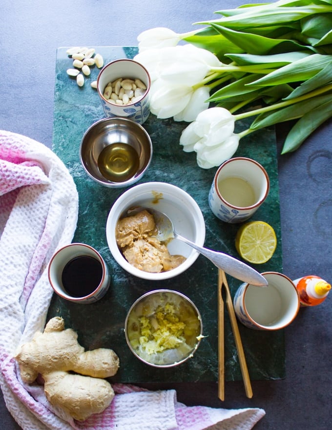 salad dressing ingredients in small bowls, a bowl ofpeanut butter, soy sauce, chilli sauce, rice vinegar, honey, grated ginger and garlic