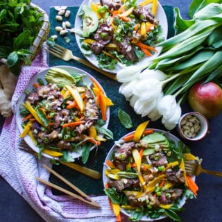 3 thai salad plates surrounded by a towel, white tulips, fresh mint