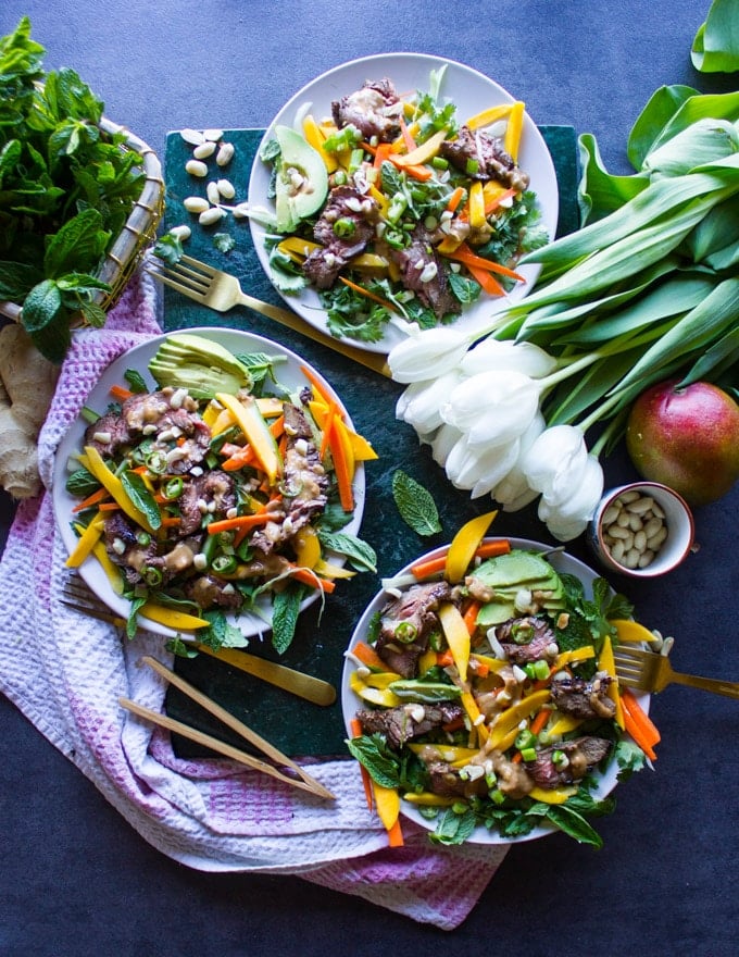 3 thai salad plates surrounded by a towel, white tulips, fresh mint