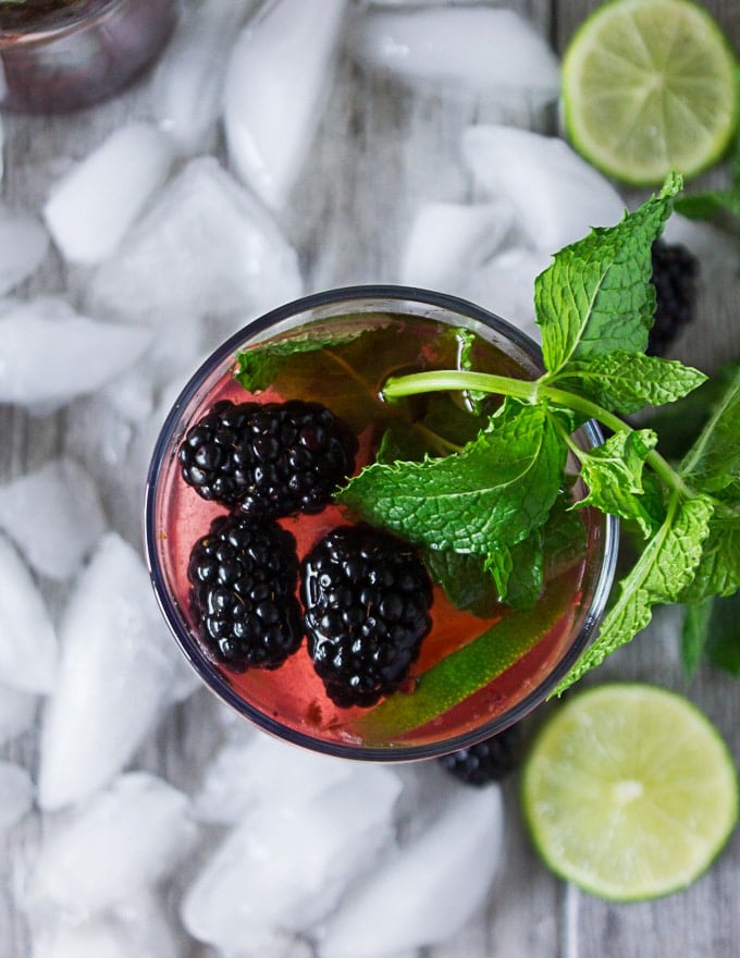 Top view of a cup of virgin mojito with blackberries and lime slices garnish