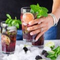 A hand holding a cup of blackberry mojitos