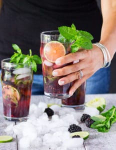 A hand holding a cup of blackberry mojitos