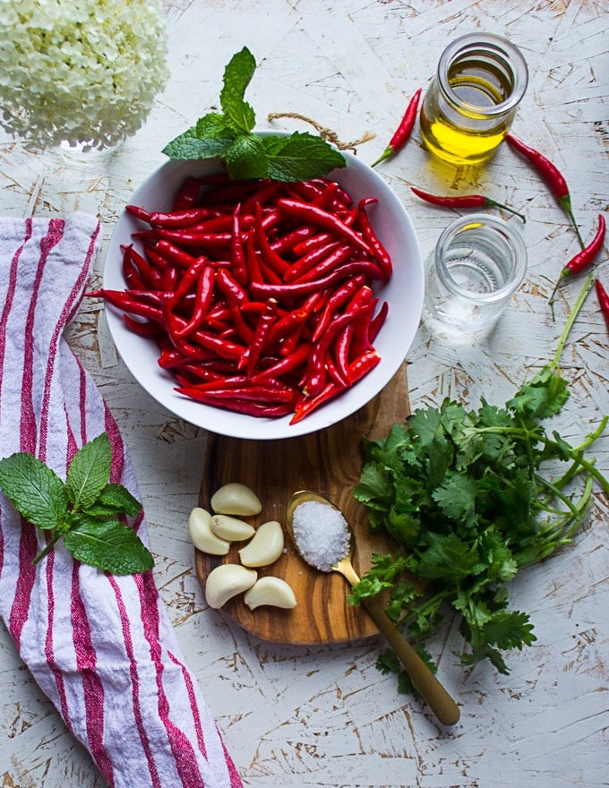 Ingredients for the hot sauce : a bowl of peppers, garlic, cilantro and mint, oil and vinegar and salt