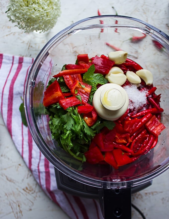 All the hot sauce recipe ingredients in a food processor bowl : the peppers, garlic, herbs, oil, vinegar