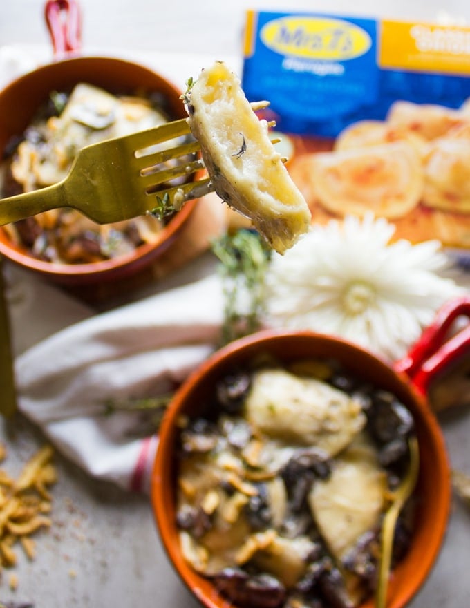 A fork holding a bitten piece of pierogies in alfredo sauce 