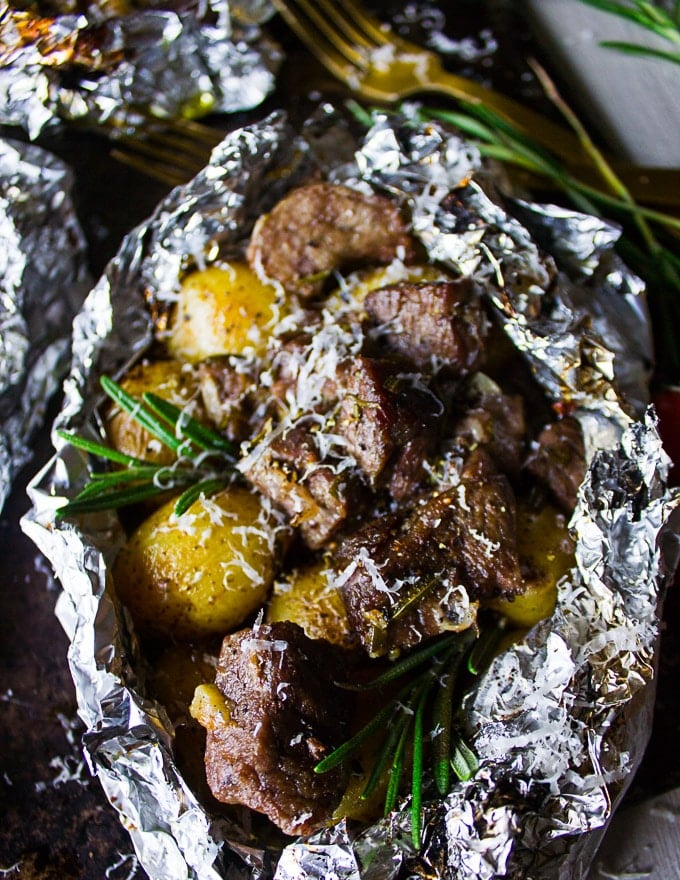 well cooked lamb and potatoes wrapped in foil packets and close up