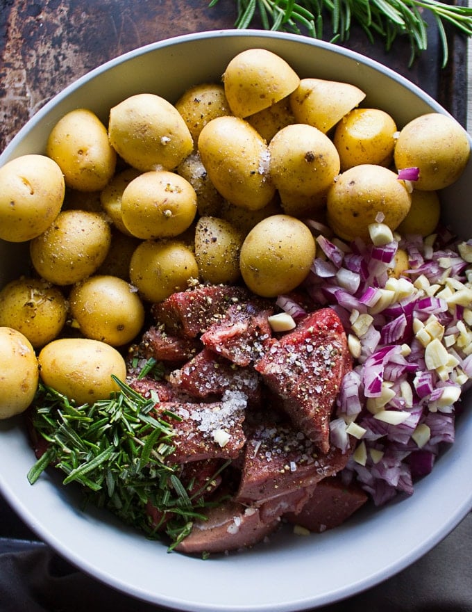 A bowl with the chopped up lamb and potatoes and the onions, garlic, rosemary added too and seasoning