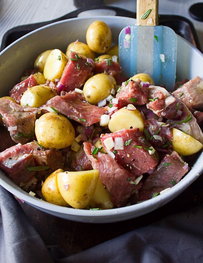 The lamb and potatoes mixture seasoned and tossed in the bowl